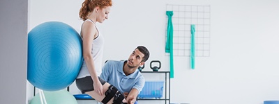 Physical therapist helping patient use yoga ball - Netsmart TheraOffice is the leading physical therapy scheduling, documentation, and billing EMR software