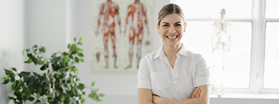 Physical therapist smiling next to a plant - Netsmart GEHRIMED is the leading EHR software platform for long-term post-acute providers of geriatric care 